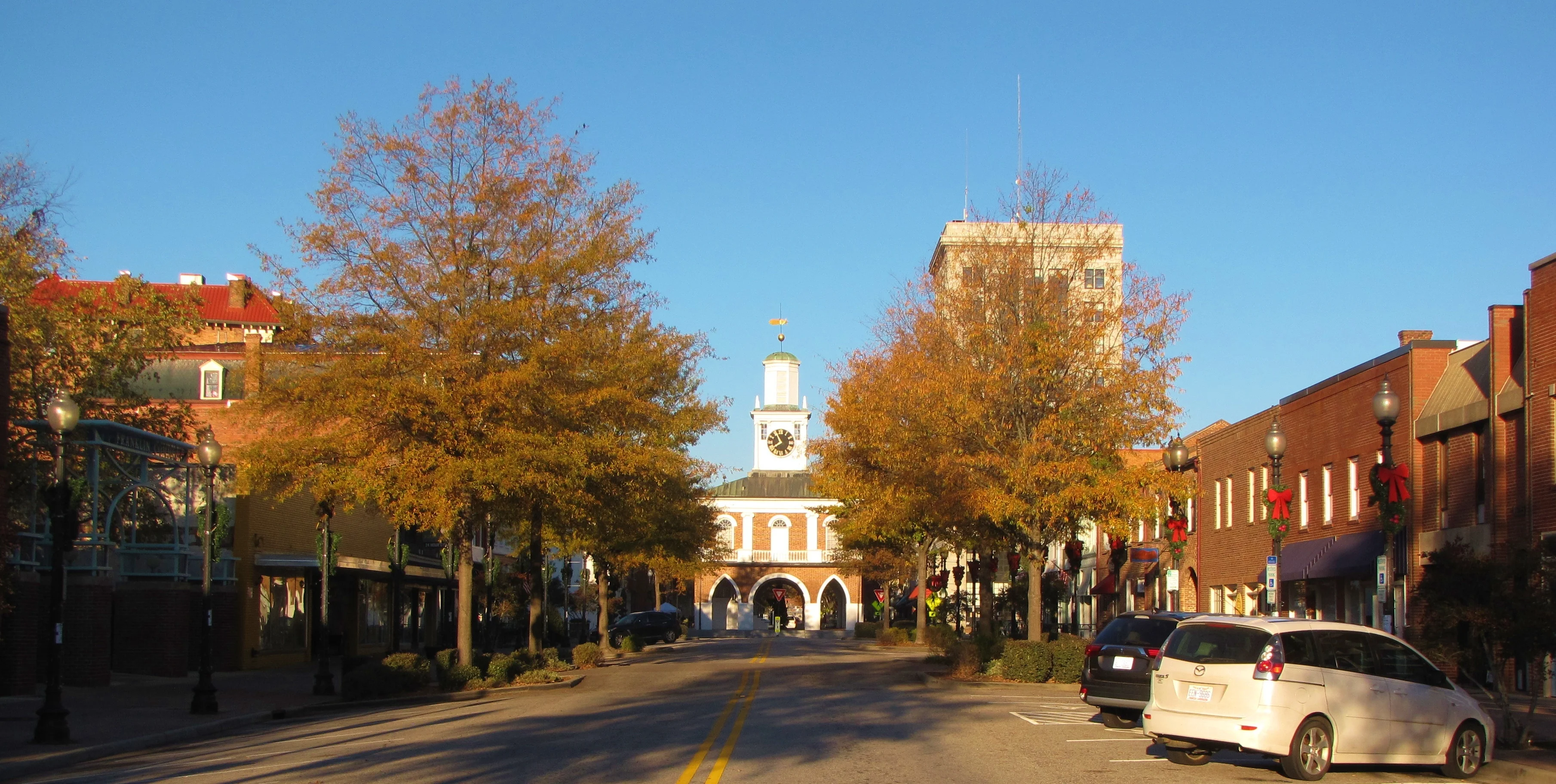 Person Street in downtown Fayetteville at golden hour, looking west toward the Market House, with glowing autumn trees lining the street